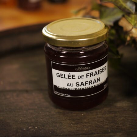 Présentation d'un pot de gelée de fraises au safran, sur le dessus d'un tonneau où un branche de lierre termine le décor